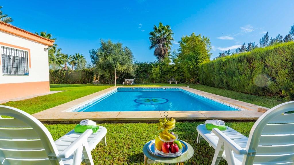 une cour avec une piscine, 2 chaises et une table avec un bol de fruits dans l'établissement Huerta Tío Pipa Aznalcázar by Ruralidays, à Aznalcázar