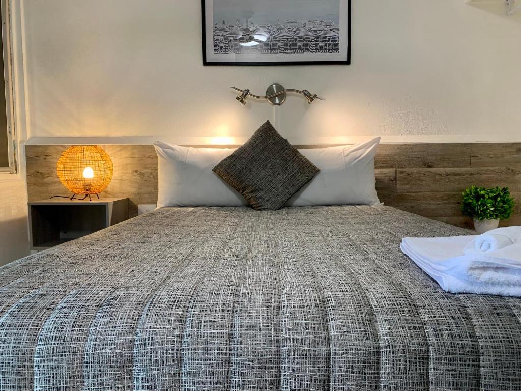 - une chambre avec un lit et une tête de lit en bois dans l'établissement Y Motels Kingaroy, à Kingaroy