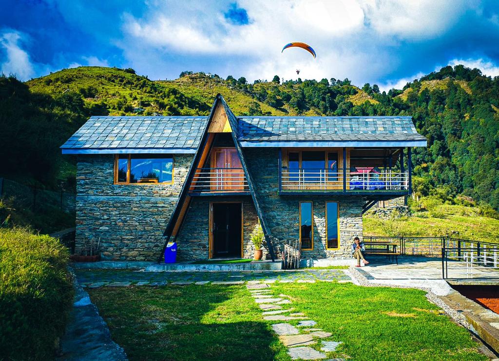 une maison avec une personne volant un cerf-volant dans l'établissement Griffons Cafe and Stay, à Dharamshala