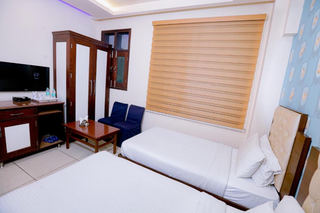 a hotel room with two beds and a television at Leela Residency in Karnal