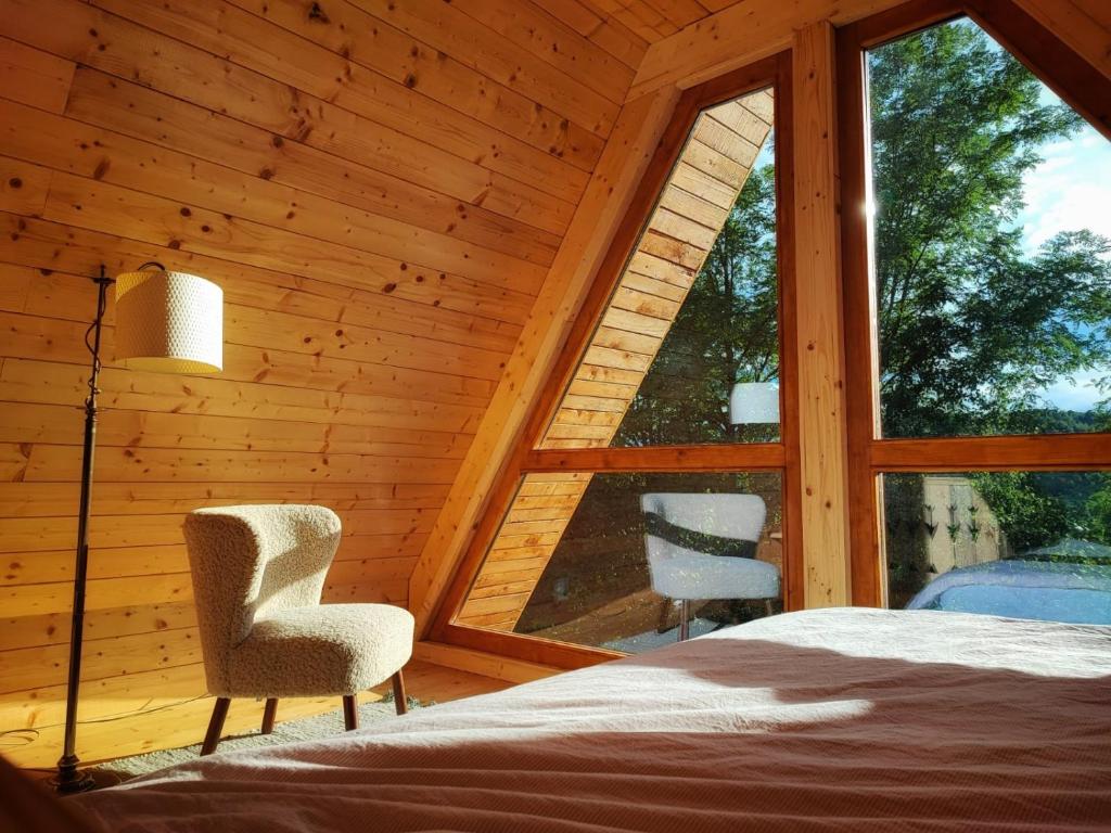 a bedroom with a bed and two chairs and a window at La sat - Blândă Mărie in Bertea
