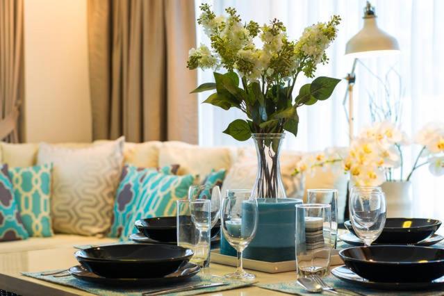 a table with plates and glasses and a vase with flowers at Baan Sandao D201 in Hua Hin