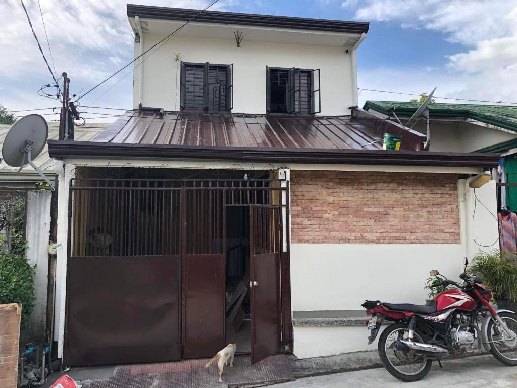 Balili Property at Metro Manila Hills Subd Rodriguez Rizal في مانيلا: منزل به دراجة نارية متوقفة أمامه