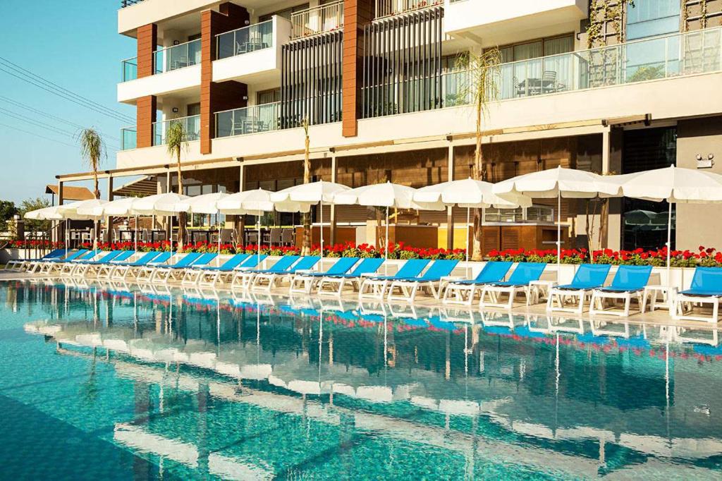 uma piscina com cadeiras e guarda-sóis azuis e brancos em Calimera Side Resort em Side