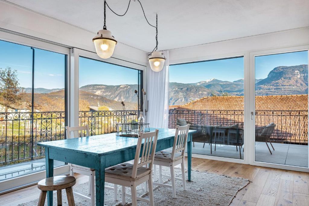 a dining room with a table and chairs and views of mountains at Eichhof Apartment Lavendel in Termeno