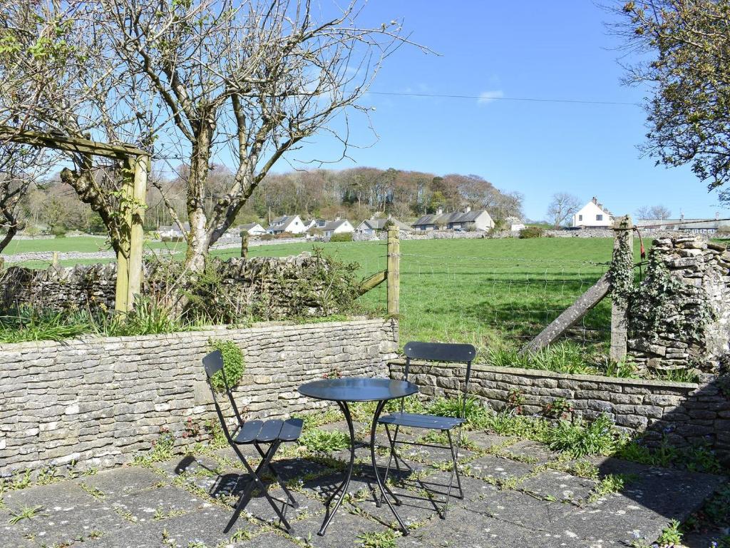 une table et des chaises dans une cour avec un champ dans l'établissement Old Chapel, à Levens