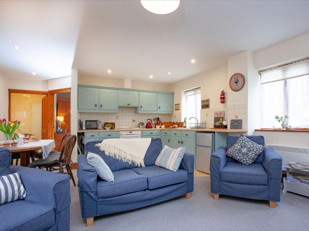 sala de estar con 2 sofás azules y cocina en The Stables en Clyst Saint Mary