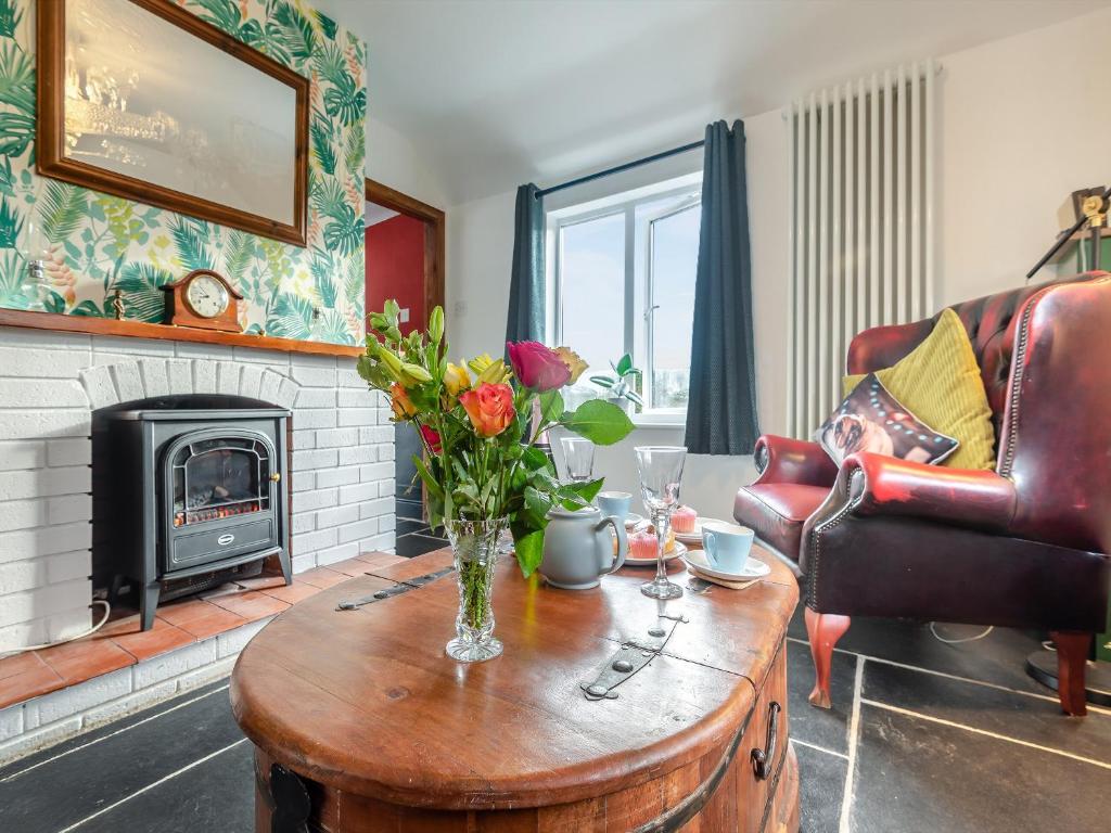 a living room with a fireplace and a table with flowers on it at White Cottage in Little Carlton