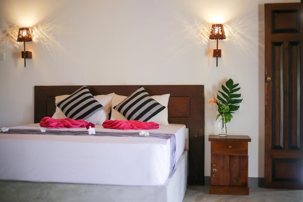 a bedroom with a large white bed with red pillows at Emma's Sea View in Hiriketiya