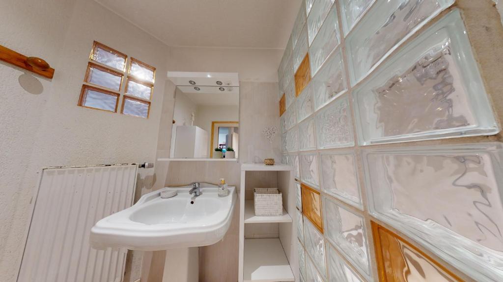 biała łazienka z umywalką i lustrem w obiekcie Magic Home - Les Taillandiers w mieście Colmar