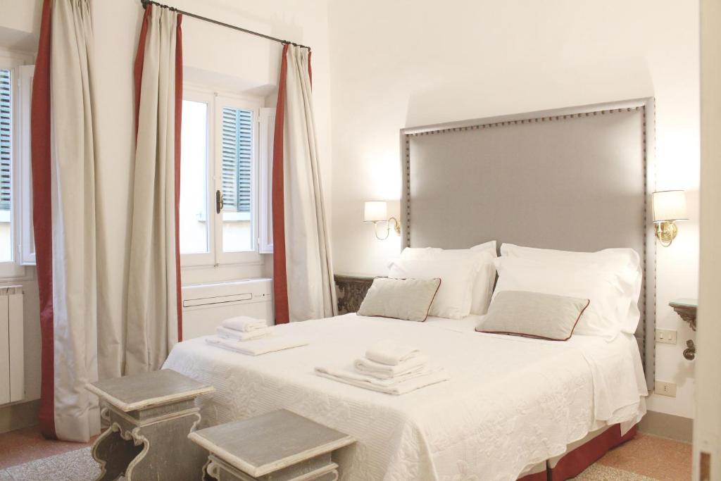 a white bedroom with a large bed with white sheets at BorgoDeGreci Apartments in Florence