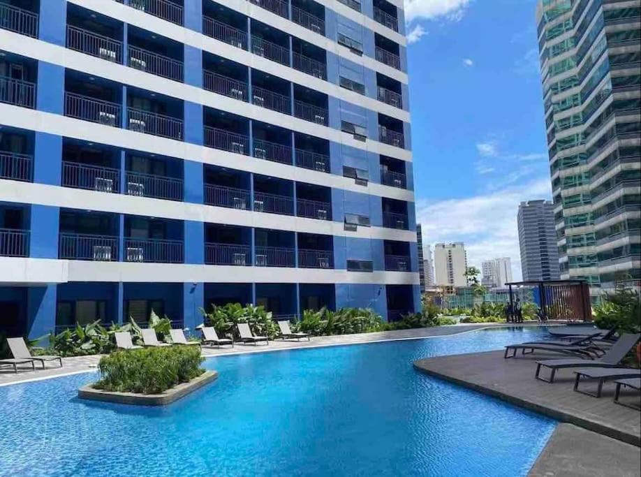 a swimming pool in front of a building at Apartment in Air Residences, Makati with wifi, Netflix, pool, mall and more in Manila