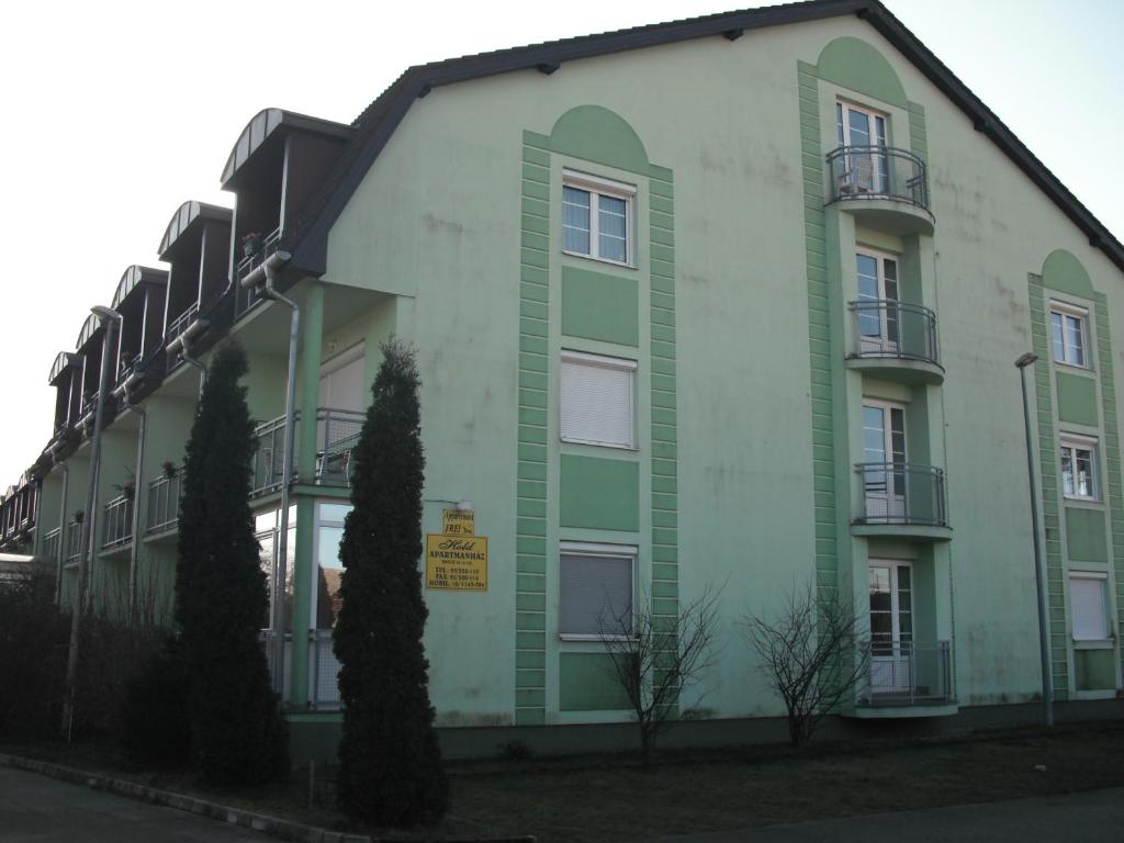 un edificio verde e bianco con alberi di fronte di Aba és Andrea Apartmanok a Sárvár