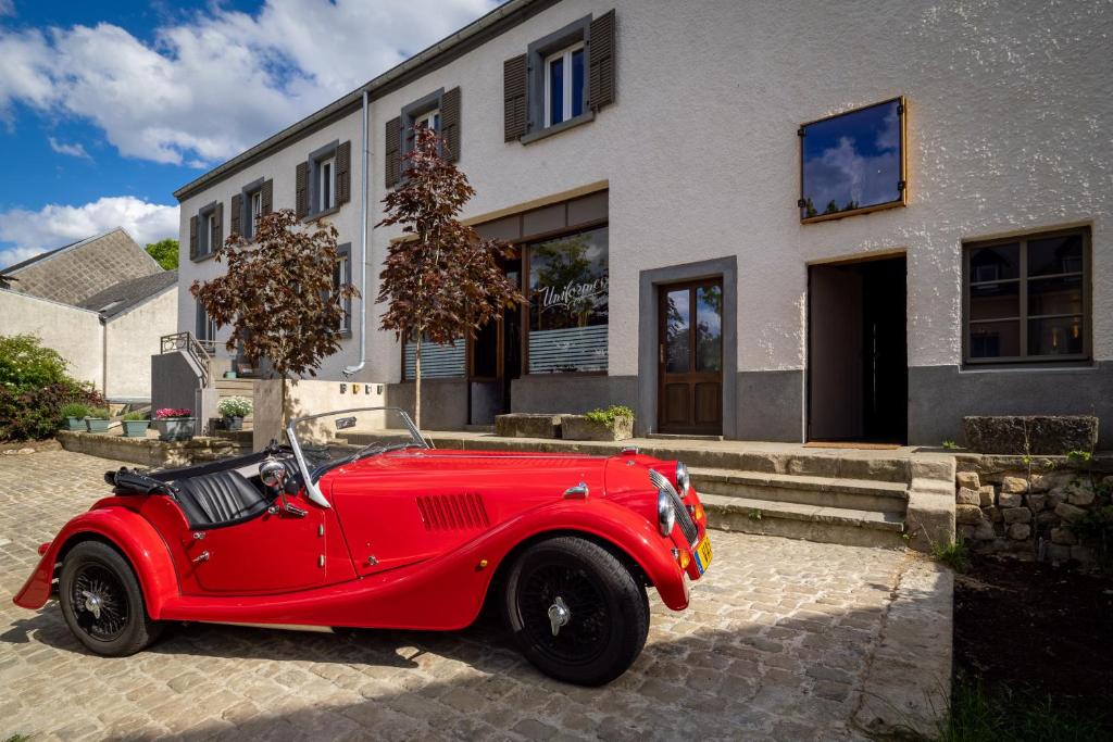 una macchina rossa parcheggiata di fronte a una casa di Tailor's Trail gîte d'adventure Beaufort Mullerthal a Beaufort