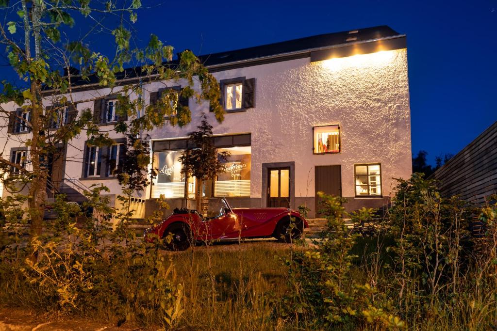 una macchina rossa parcheggiata di fronte a una casa di notte di Tailor's Trail gîte d'adventure Beaufort Mullerthal a Beaufort