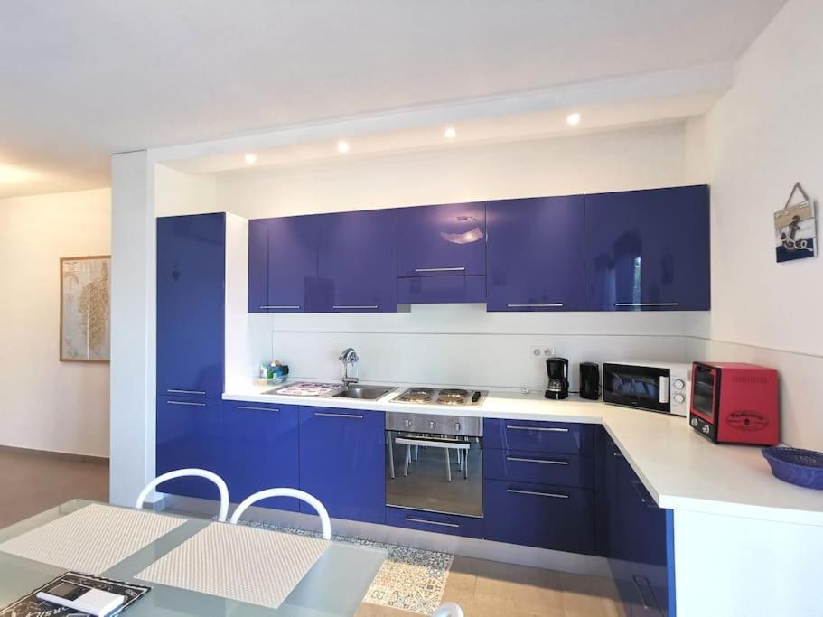 una cucina con armadi blu e un tavolo con un apparecchio rosso di Joli appartement face à la mer- St Florent a Saint-Florent