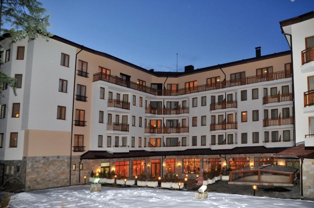 un grande edificio con neve di fronte di Villa Park Guest Apartments a Borovets