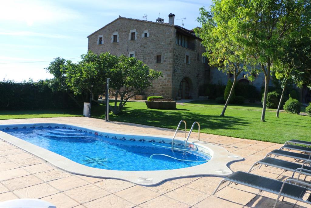 una piscina frente a una casa de piedra en Masia Cal Mas, en Sant Serni de Llanera