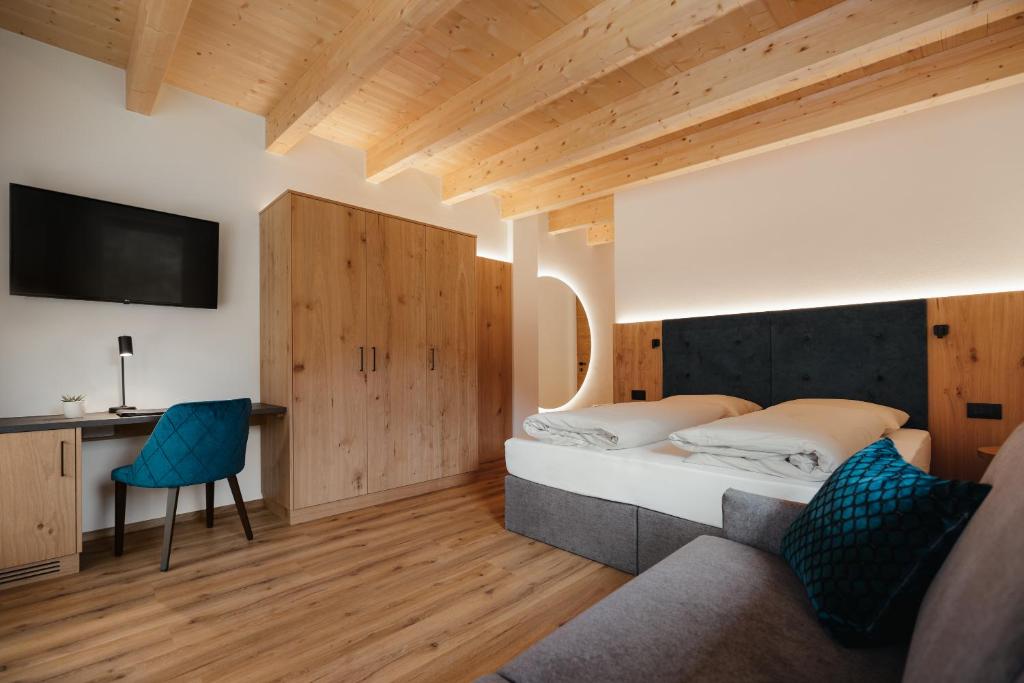 1 dormitorio con 1 cama, escritorio y TV en Aria de Munt, en San Vigilio Di Marebbe