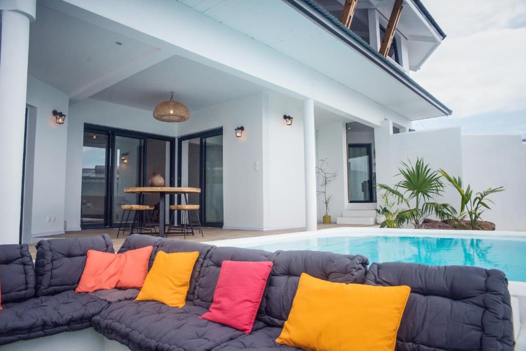 - un canapé avec des oreillers colorés installé à côté de la piscine dans l'établissement Villa romantique, Rêve d'ailleurs, saint leu, la Réunion, à Saint-Leu