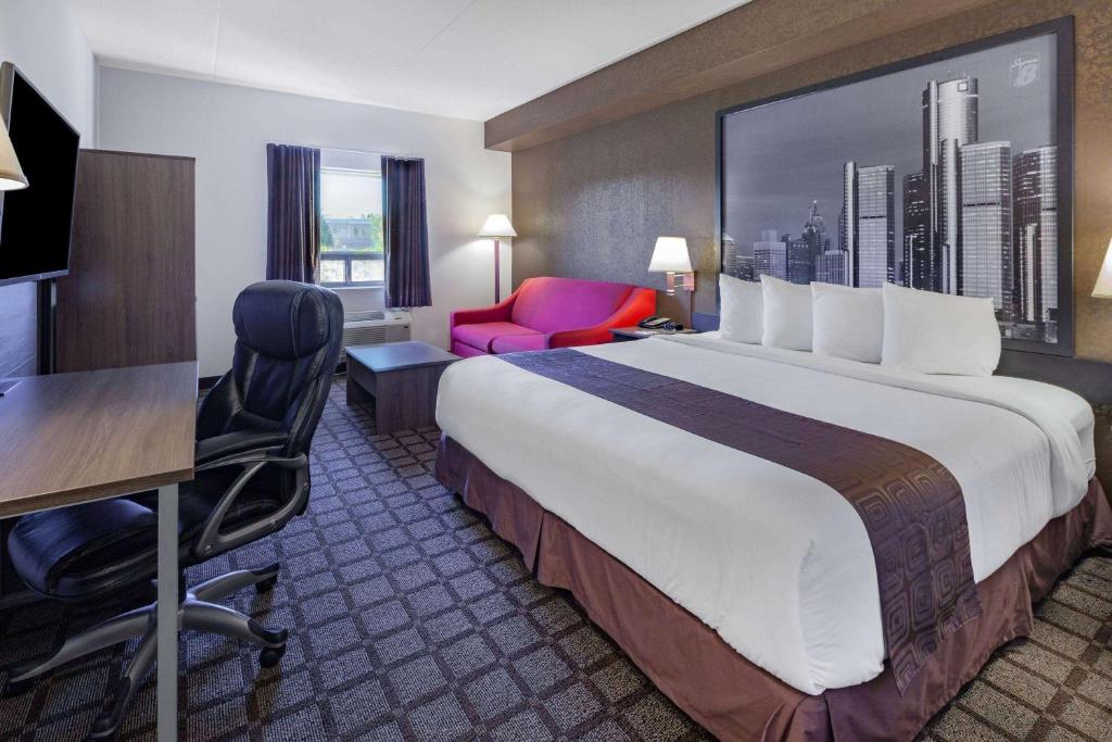 ein Hotelzimmer mit einem großen Bett, einem Schreibtisch und einem Stuhl in der Unterkunft Super 8 by Wyndham Ambassador Bridge Windsor ON in Windsor