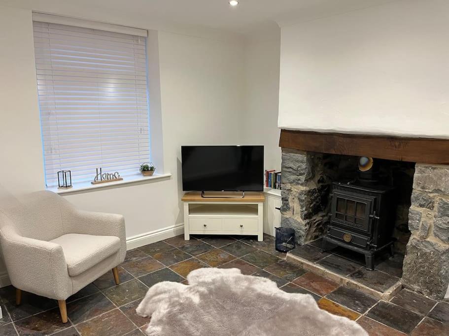 a living room with a fireplace and a television at Mount Cottage in Conwy