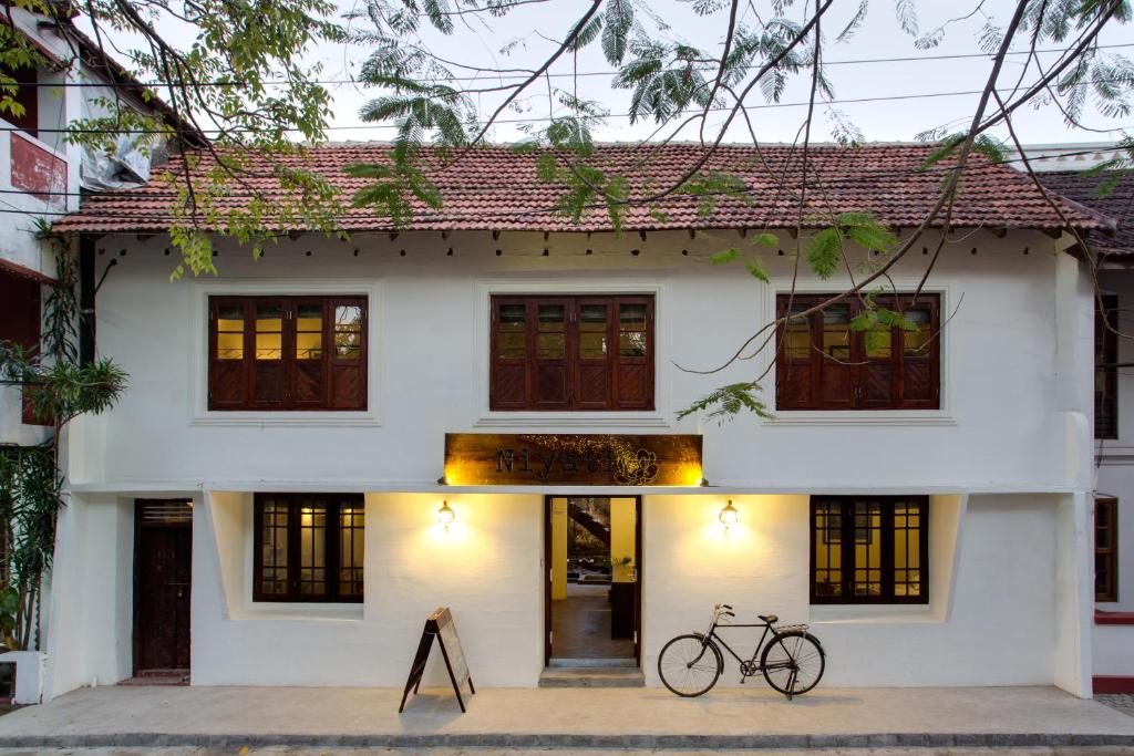 una bicicleta estacionada frente a una casa blanca en Niyati - Boutique Stay, en Kochi