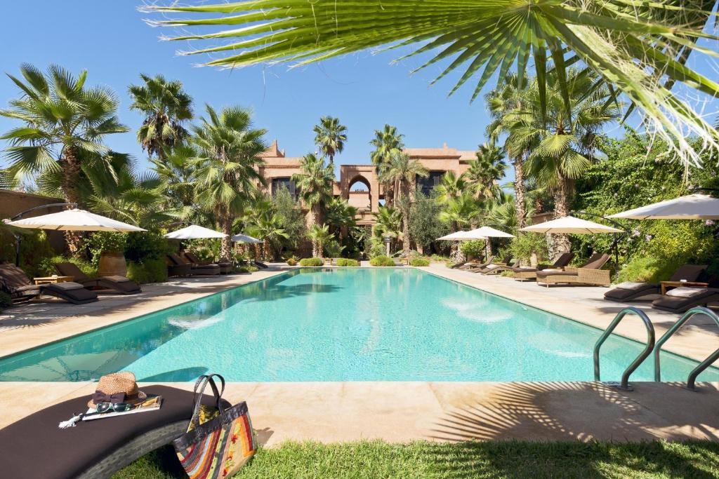 a pool at a resort with palm trees and umbrellas at Tigmiza Boutique Hotel & Spa in Marrakech