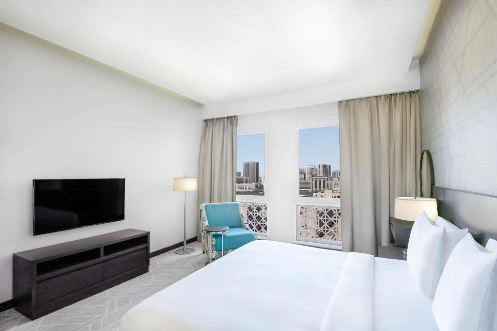 Hyatt Place Dubai Wasl District في دبي: غرفه فندقيه سرير كبير وتلفزيون