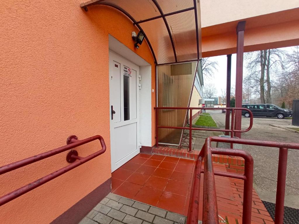 um edifício laranja com uma porta branca e um alpendre em BOSiR Białogard em Bialogard