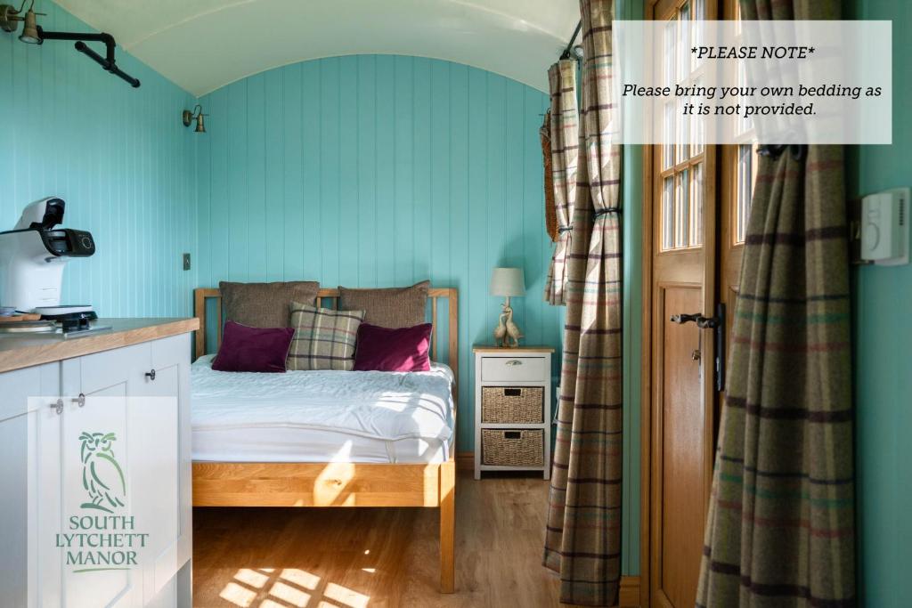 a bedroom with a bed with blue walls at Glamping at South Lytchett Manor in Poole