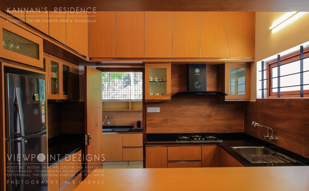特里凡得琅的住宿－Nirvana Home stay TVM -allure，厨房配有木制橱柜和不锈钢冰箱。