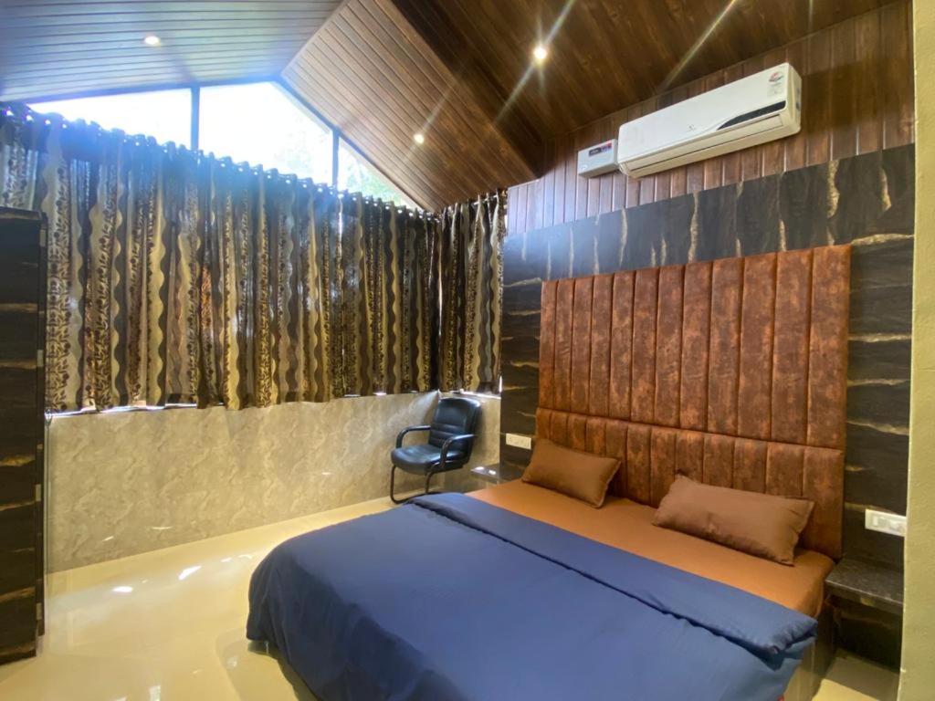 a bedroom with a bed and a chair in it at Mount Bungalows-Mount Paradise-6BHK-PVTPOOL in Lonavala