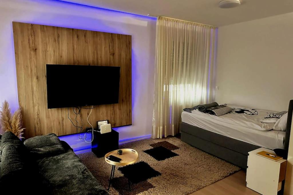 ザグレブにあるAtraktivan studio apartmanのリビングルーム(ソファ、紫色の照明付きテレビ付)