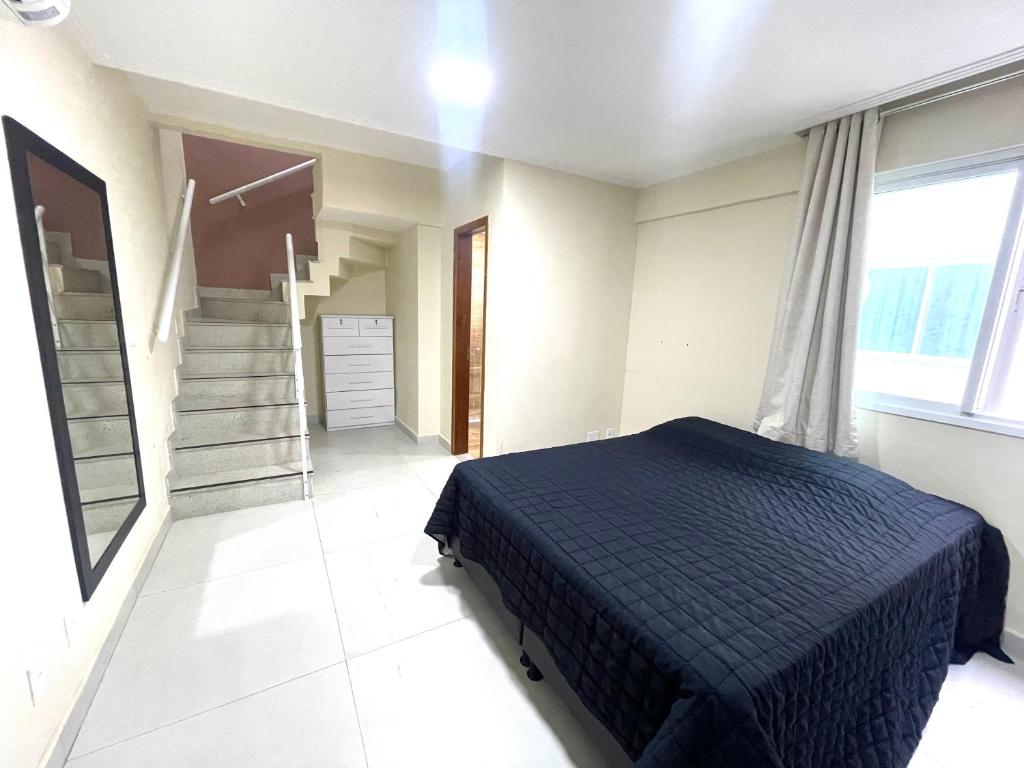 a bedroom with a bed and a staircase in it at Cobertura Luxo com Jacuzzi Orla Praia Grande in Arraial do Cabo