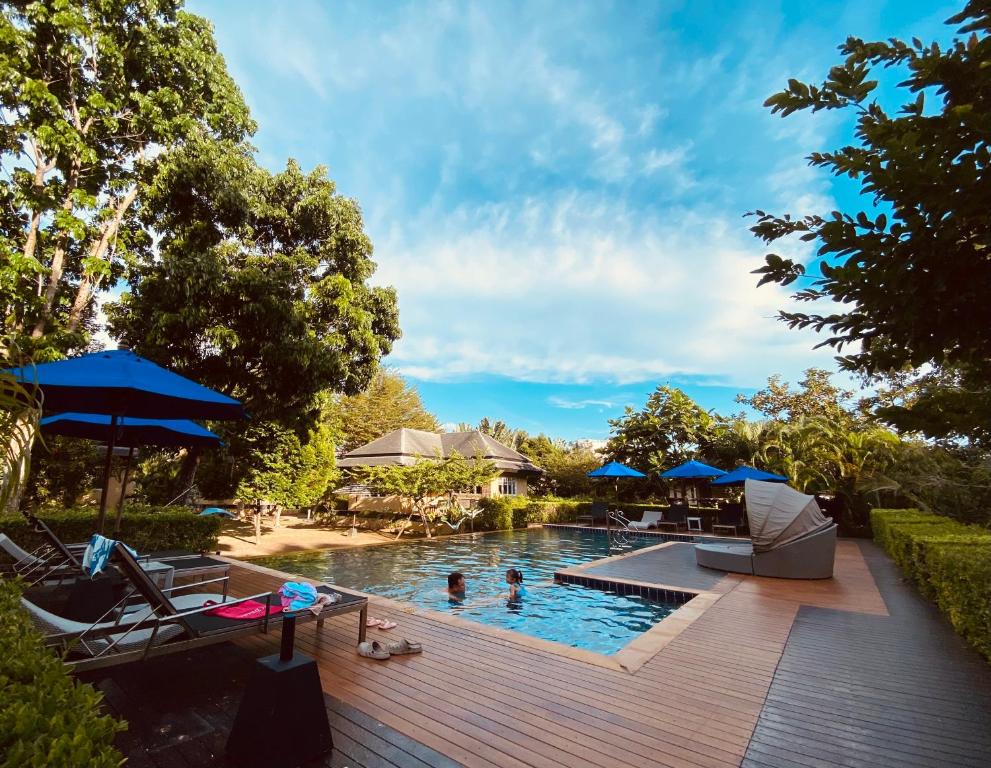 una piscina con sillas y sombrillas en una terraza de madera en Perennial Resort, en Nai Yang Beach