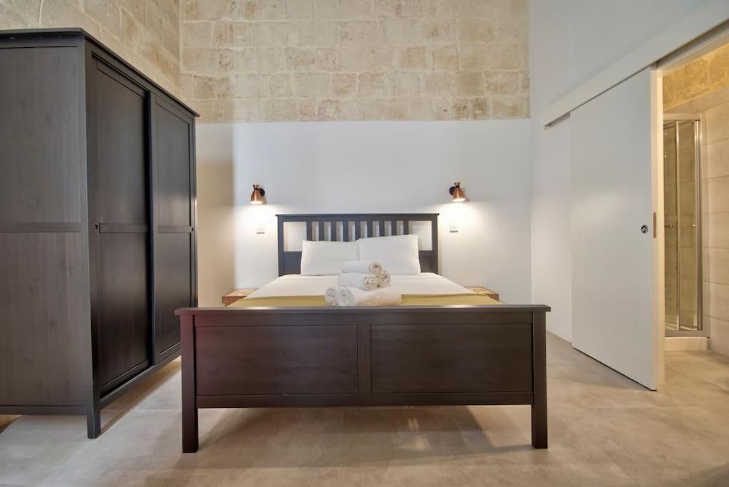 a bedroom with a large bed with a wooden dresser at Vallettastay Old Lodge Apartment 3 in Valletta