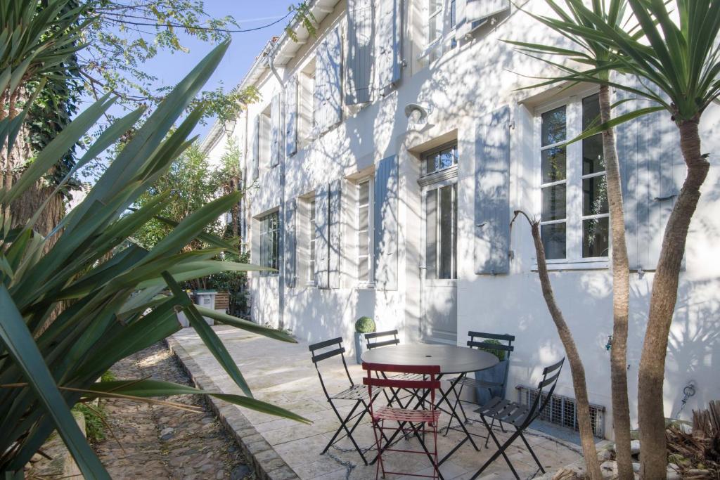 un patio con mesa y sillas frente a un edificio blanco en Violette maison de charme au cœur de St Martin, en Saint-Martin-de-Ré