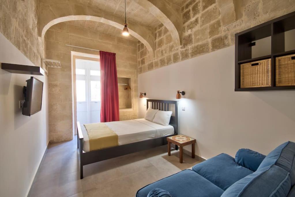 a bedroom with a bed and a blue couch at Vallettastay Old Lodge Apartment 4 in Valletta