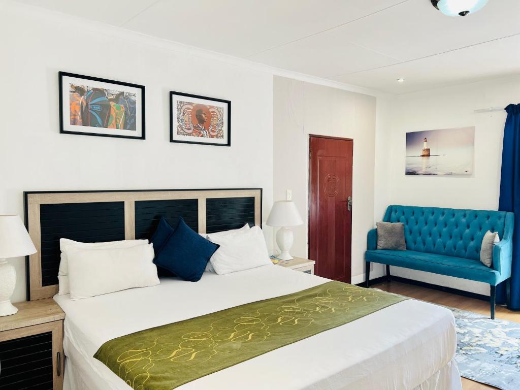 um quarto com uma cama grande e uma cadeira azul em Airport Royal Guest House em Kempton Park
