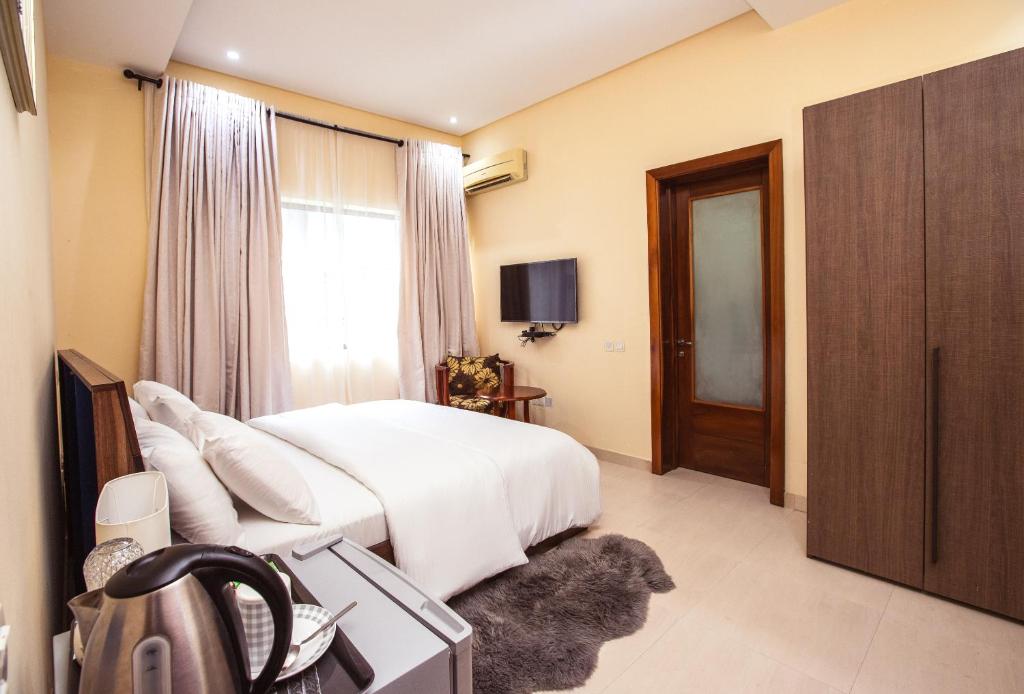 um quarto com uma cama branca, uma janela e uma televisão em Rushmore - Premier 2 Room em Lagos