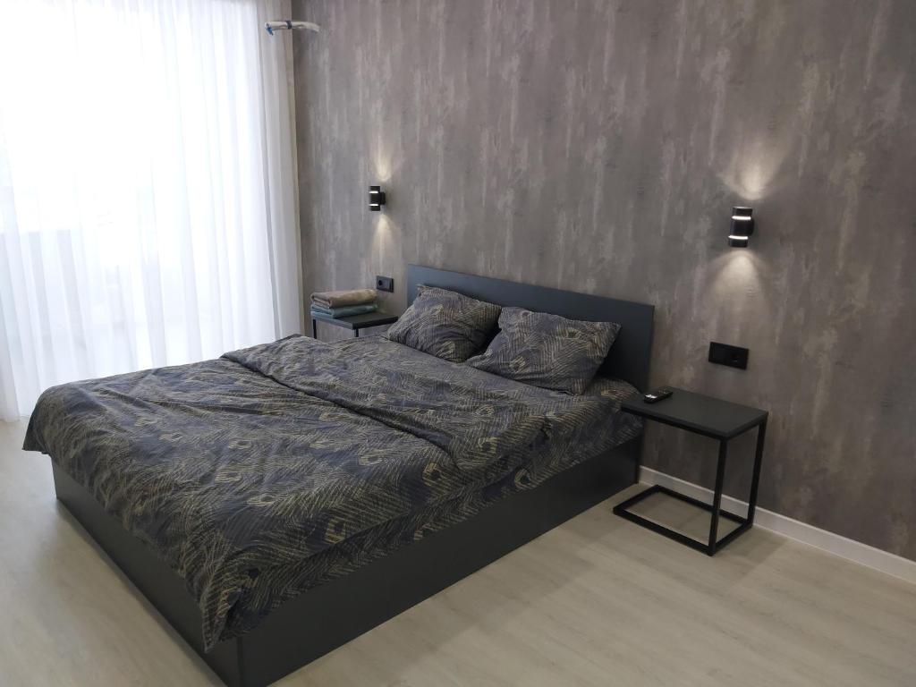1 dormitorio con 1 cama y mesa auxiliar en Люкс Апартаменты Gray Pearl на Подолье, en Vínnytsia