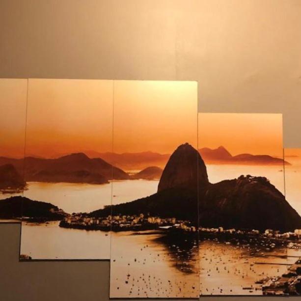 una pintura de una montaña en el agua con la puesta de sol en Luxo sala e quarto quadra da praia Copacabana, en Río de Janeiro