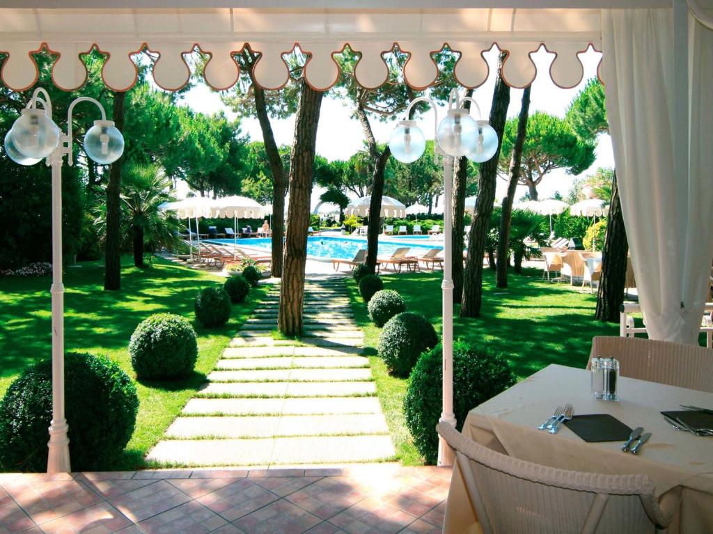 um jardim com uma mesa e uma piscina ao fundo em Park Hotel Maracaibo em Lido di Jesolo