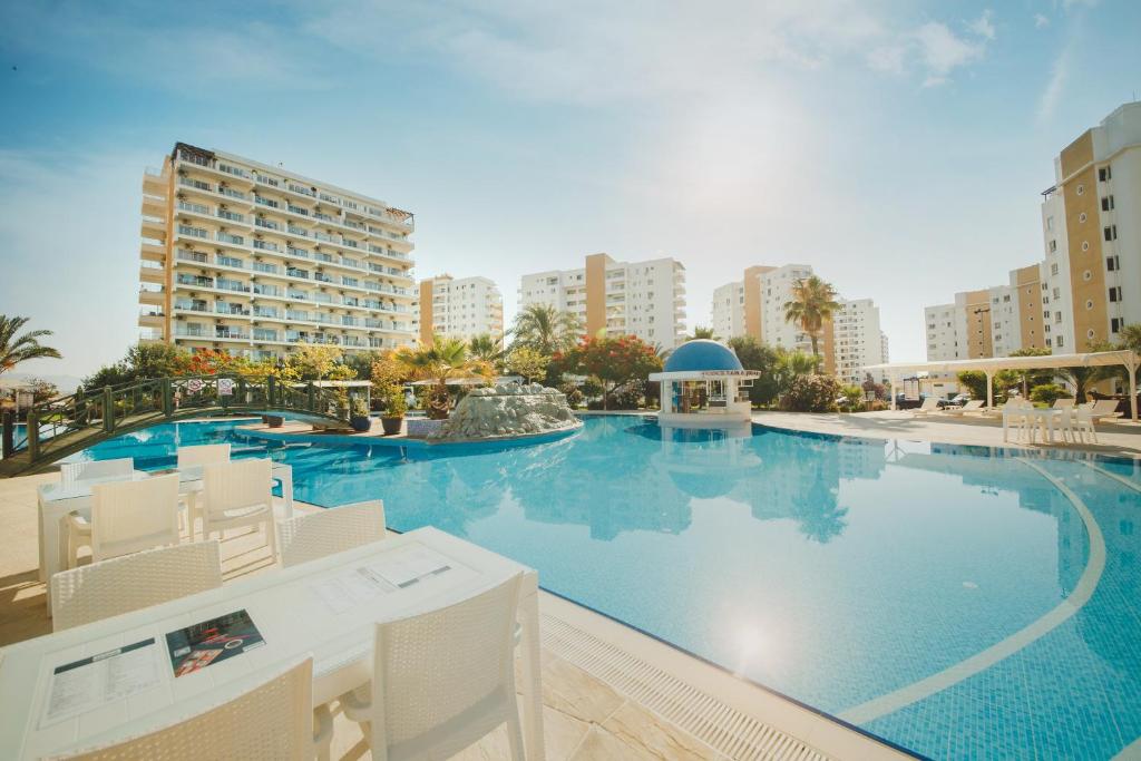 a large swimming pool with white chairs and buildings at Andreanius Caesar Resort & Spa Studio with Niche, Stunning Balcony View in Iskele
