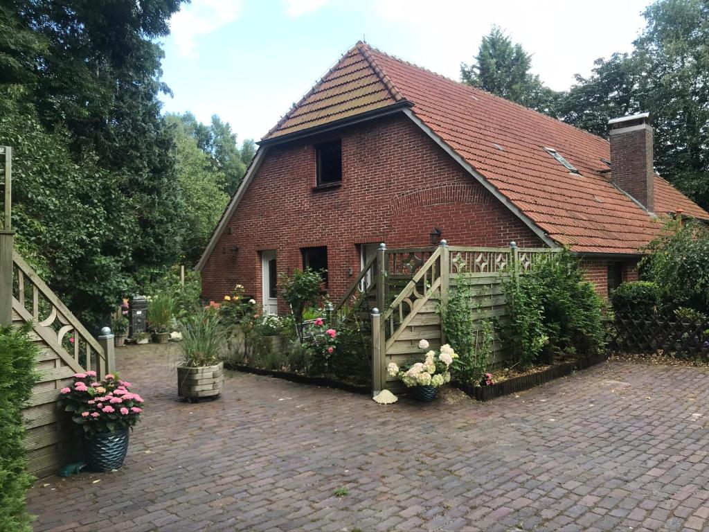 een stenen huis met een hek en een stenen tuin bij Ferienwohnung Gulfhaus, mit Sauna und großem Garten in Apen