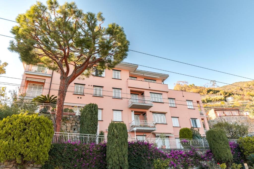 un edificio rosa con un albero di fronte di 086 - Sunshine Home, 5 minuti dalla spiaggia, VISTA MARE - PARCHEGGIO PRIVATO GRATIS INCLUSO a Ospedaletti