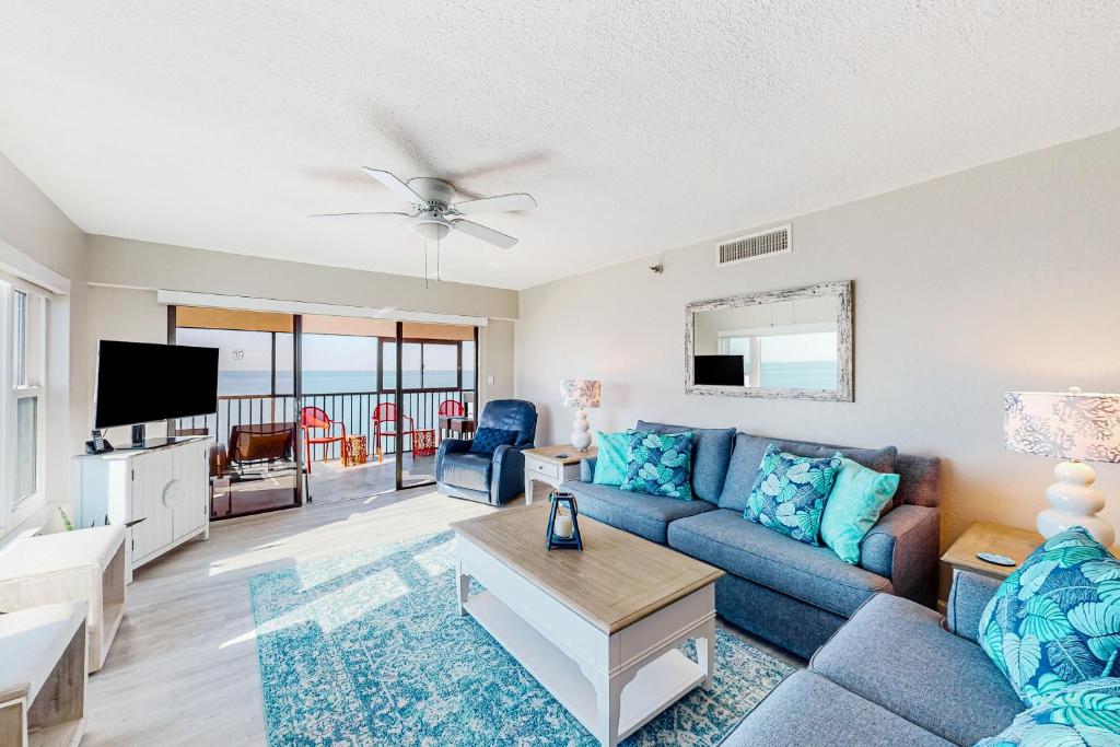 uma sala de estar com um sofá azul e uma televisão em Arie Dam 401 em St. Pete Beach
