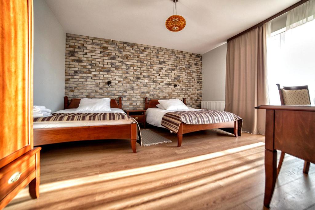 a bedroom with two beds and a brick wall at Hotel Pan Tadeusz in Osielsko