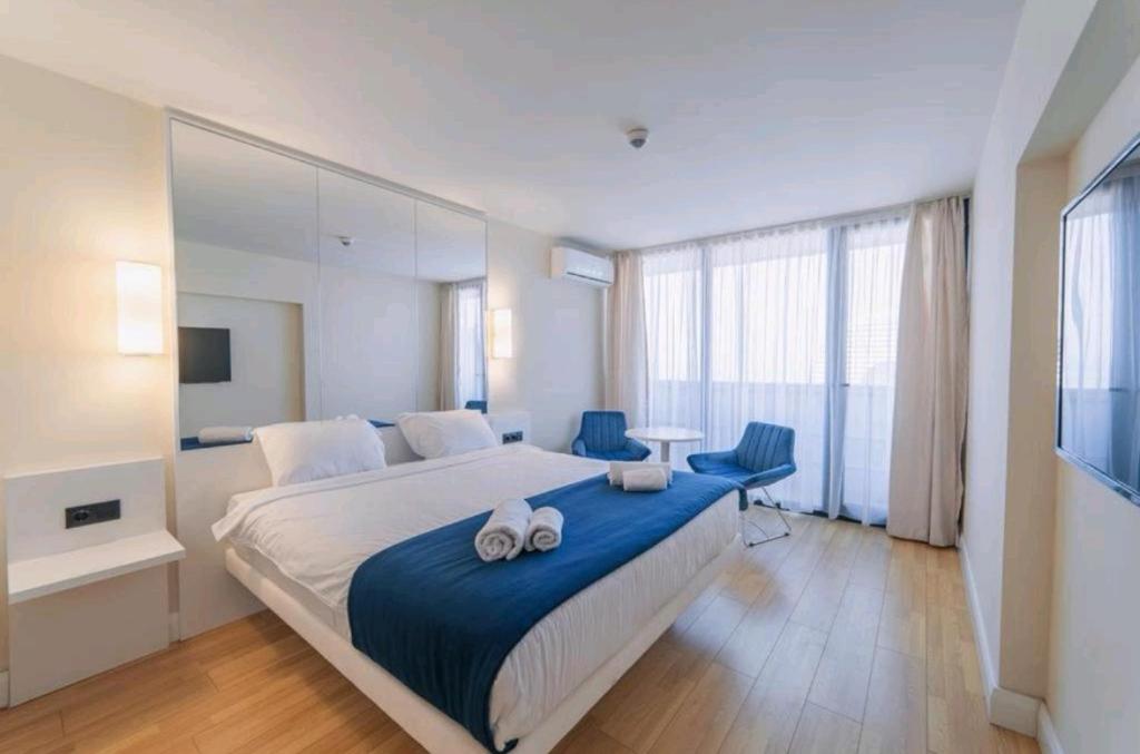 een slaapkamer met een groot bed en 2 blauwe stoelen bij Orbi City in Batoemi